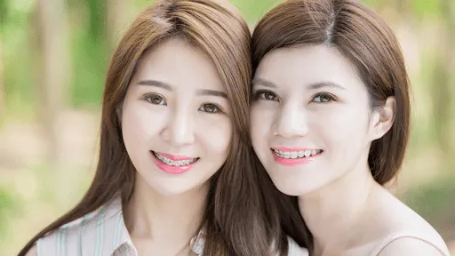 Two smiling people wearing braces